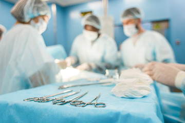Tools for the operation in the foreground and a team of surgeons in the background performing the...