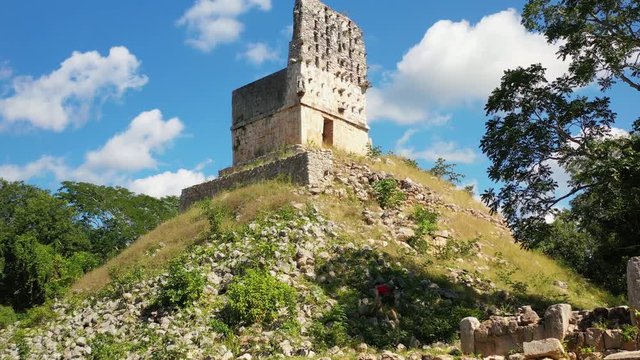 Aerial, rising, drone shot of a man climbing at the Labna ruins, on a sunny day, in Yucatan, Mexico
