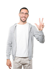 Young man making a number three gesture