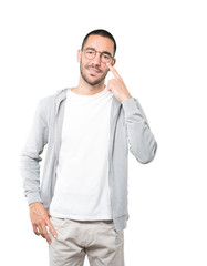 Fototapeta premium Friendly young man making a gesture of being careful with his hand pointing at his eye