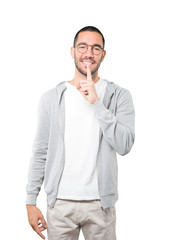 Fototapeta premium Happy young man asking for silence gesturing with his finger