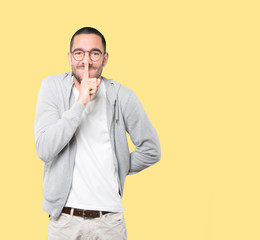 Amazed young man asking for silence gesturing with his finger