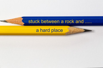two sharpened pencils in blue and yellow point in different directions isolated against a white...