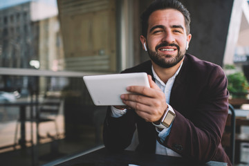 Cheerful Hispanic entrepreneur with tablet looking at camera