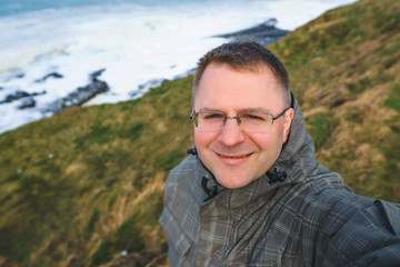 man in glasses making selfie at coastline