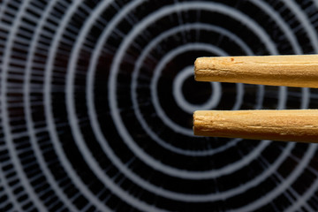 Concept photo, macro from the tip of two Japanese chopsticks over an intentionally blurred plate with concentric rings