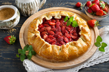 Baked galette or open strawberry pie on the table.