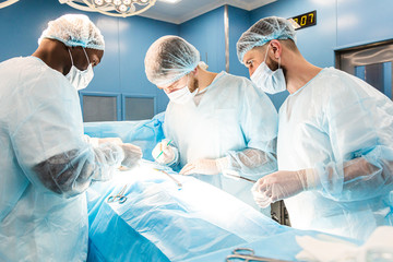 An international team of doctors performs a complex surgical operation on a patient under anesthesia. Modern operating room and experienced surgeons save lives