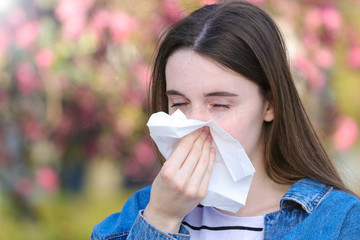 Girl with polen allergy over flowers in early spring