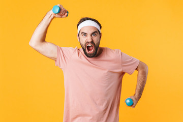 Image of muscular athletic young man having fun and lifting dumbbells