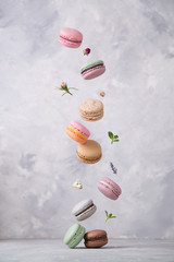Sweet macaroons cookies falling in motion on grey background. Pastel colored flying macaroons with ingridients. Food, culinary and cooking concept levitation