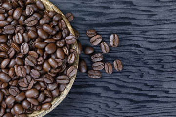 Coffee beans in a wooden plate on a wood grain background