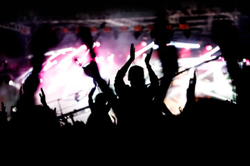 The crowd enjoys a music show. Black silhouette.