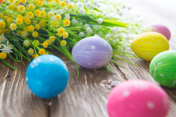 Fototapeta na wymiar Happy Easter. Colorful easter eggs and flowers on wooden table.