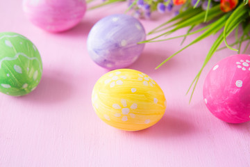 Easter eggs with wild flowers on a wooden pink table background