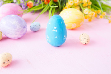 Easter eggs with wild flowers on a wooden pink table background