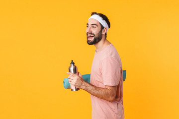 Image of athletic young man carrying fitness mat and water bottle