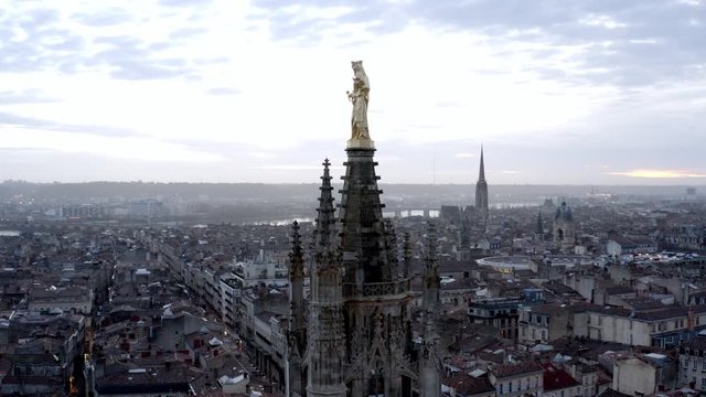 Madonna and child golden statue on top of Pey Berland bell tower on St. Andrew Cathedral, Bordeaux France, Aerial drone lift reveal shot