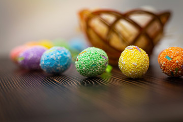 Close up of the colorful easter eggs and white eggs in a nest with hay on a dark wooden background. Easter holidays concept. April vibes.