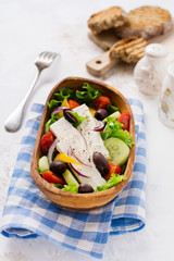 Greek salad in wooden plate on a white background. Traditional Greek dish. Selective focus. Top view.