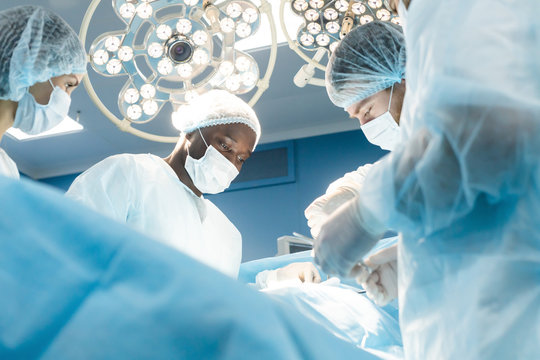 An international team of doctors performs a complex surgical operation on a patient under anesthesia. Modern operating room and experienced surgeons save lives