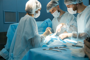 An international team of doctors performs a complex surgical operation on a patient under anesthesia. Modern operating room and experienced surgeons save lives