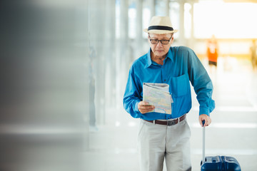 Senior man traveling with luggage checking city map and sightseeing. Senior man Travel and tourism concept.