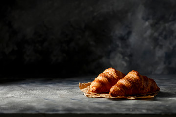 Fresh croissant on dark mood background and copy space for your product. 