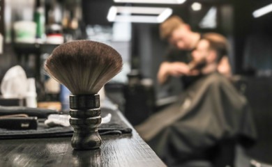 Brush in focus. Close up photo of a special barber tool standing on a counter in a barbershop,...