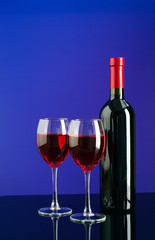 Glasses and bottle of wine on bright blue background