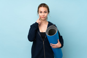 Teenager Russian girl holding mat isolated on blue background and looking front