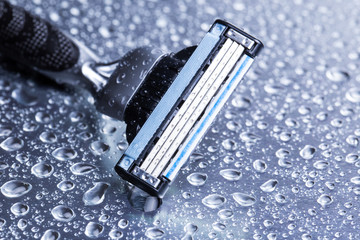 Razor close-up with water drops on a gray background.