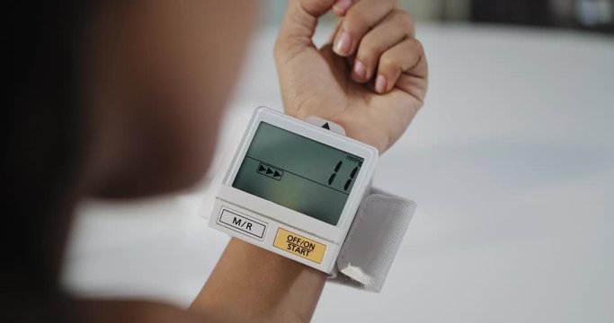 Young black woman measuring blood pressure with medical device at home. African American girl checking health. Hispanic people and healthy lifestyle