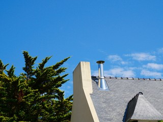 Hausdach mit Kamin vor blauem Himmel