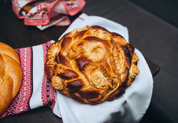 Ukrainian decorated fresh loaf with salt lies on the table, next to the embroidered towel....