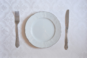 The texture on the white fabric. a linear pattern. White plate, knife and fork. tableware