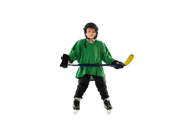 Little hockey player with the stick on ice court, white studio background. Sportsboy wearing equipment and helmet, practicing, training. Concept of sport, healthy lifestyle, motion, movement, action.