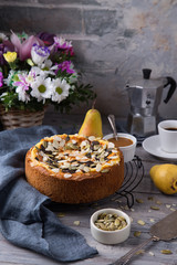 Autumn homemade pear pie with pumpkin seeds and almond petals on wood grey table and coffee cup
