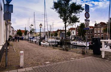 Goes, the netherlands, august 2019. View of the small and pretty harbor. It creeps between the historic houses of the center, along the piers trees and lampposts with planters.