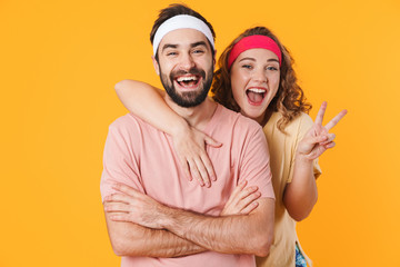 Portrait of athletic young couple smiling and gesturing peace fingers