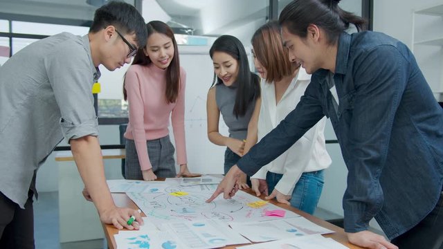 Slow motion : Group of asian creative employee standing and brainstorming stategy plan in happy workshop at creative workplace. Effective meeting, productive workshop and synergy business concept