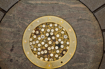 Goes, the netherlands, August 2019. In the streets of the historic center, a manhole cover covered with euro coins minted. An engraving reports the ancient saying: money has no smell.