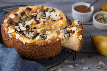 Cheesecake Tart With Pears, Pumpkin Seeds and Almond Petals On Wooden Table with Caramel. Fall Baking Concept.