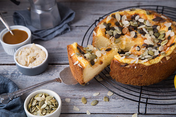 Autumn homemade pear pie with pumpkin seeds and almond petals on wood grey table and coffee cup