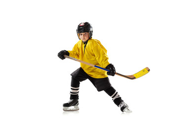 Little hockey player with the stick on ice court and white studio background. Sportsboy wearing...
