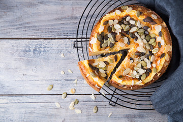 Pears and cheese pie with bowl of caramel, pumpkin seeds and almond petals. Top view. Copy space flat lay