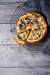 Pears and cheese pie with bowl of caramel, pumpkin seeds and almond petals. Top view. Copy space flat lay
