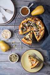 Pears and cheese pie with bowl of caramel, pumpkin seeds and almond petals, old spoon and fork. Top view. Copy space flat lay
