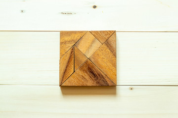 Wood tangram puzzle in square shape on white wood background