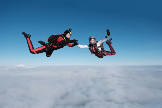 Skydiving. Guy and girl fly together in the sky above white clouds